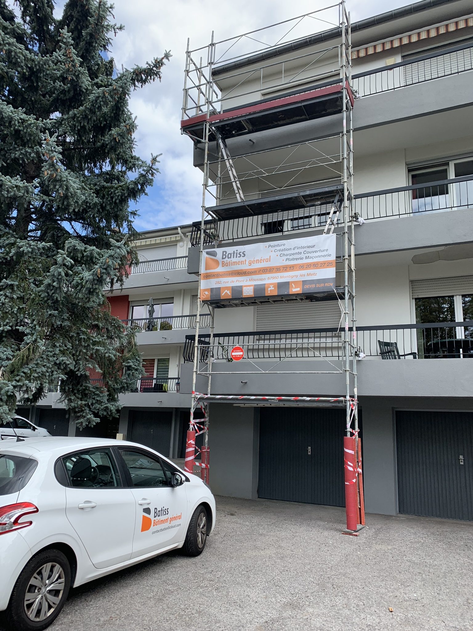 Échafaudage contre un immeuble avec la bâche Batiss, voiture Batiss devant