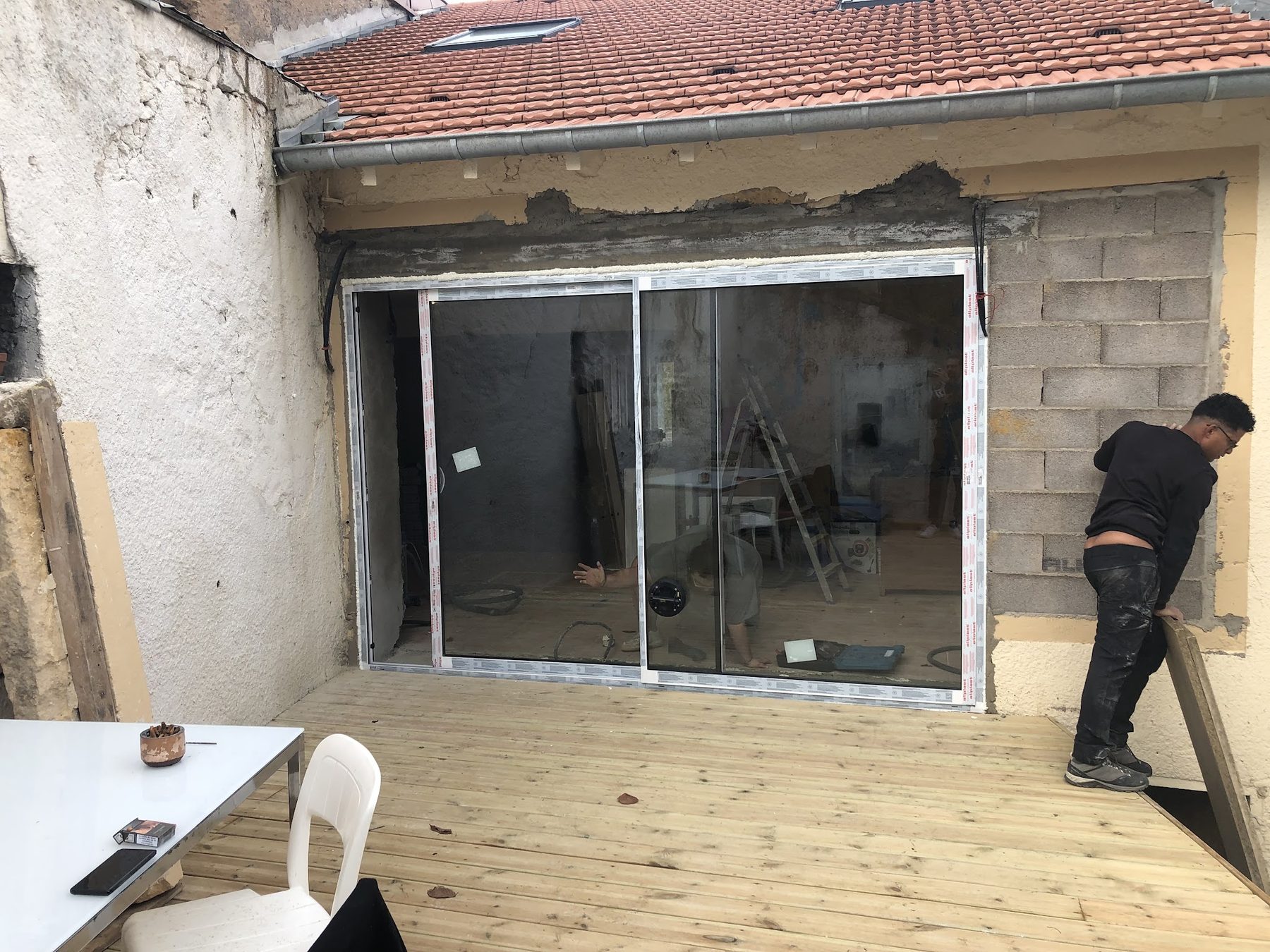 Grande baie coulissante posée sous un toit de tuiles, terrasse en bois neuve